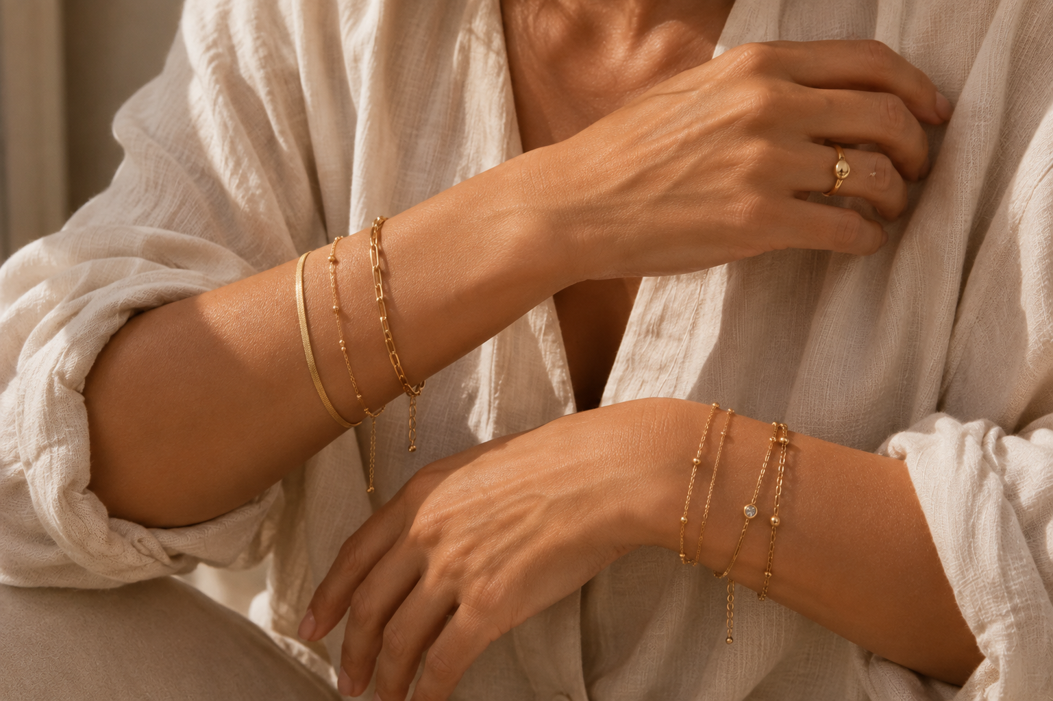 Gold bracelets styled on both wrists in warm natural light.