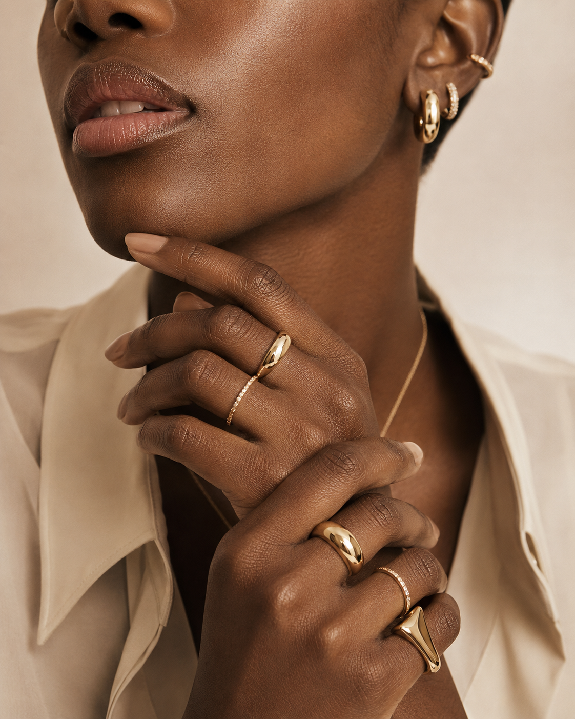 Woman styling multiple gold rings in an editorial close-up.