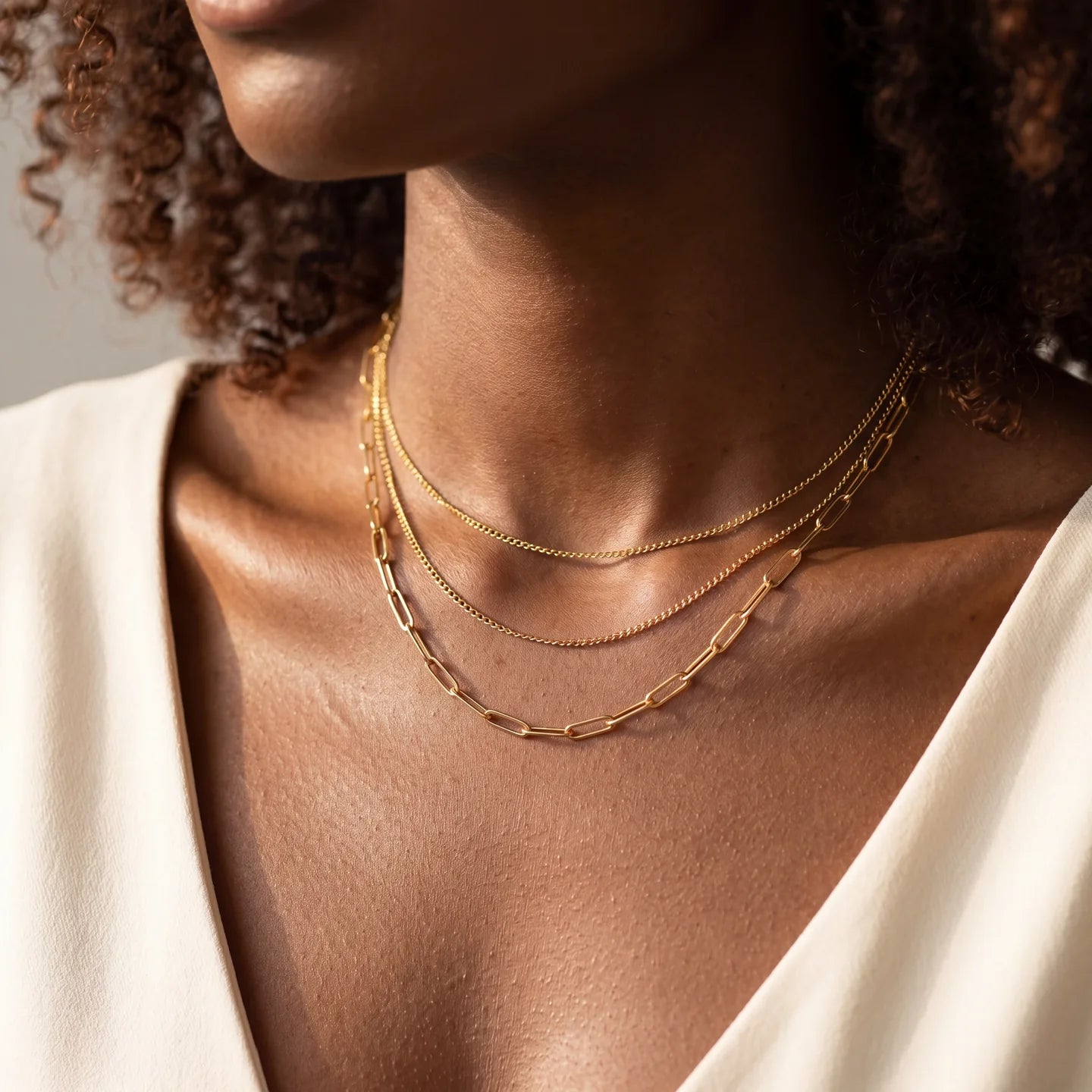 Layered gold necklaces styled over a white neckline.