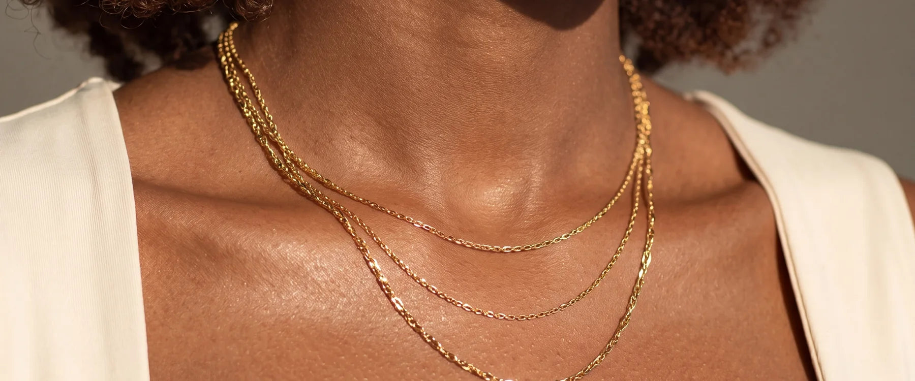 Layered gold necklaces styled on a woman in a white top.